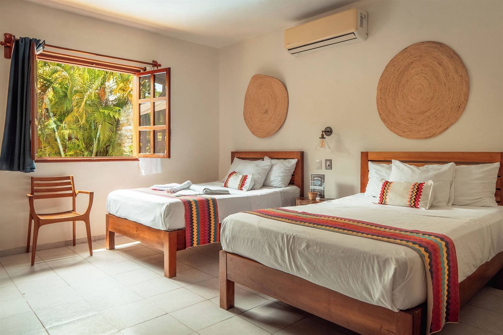 Standard room with two beds, Mexican striped throws and a window to the garden